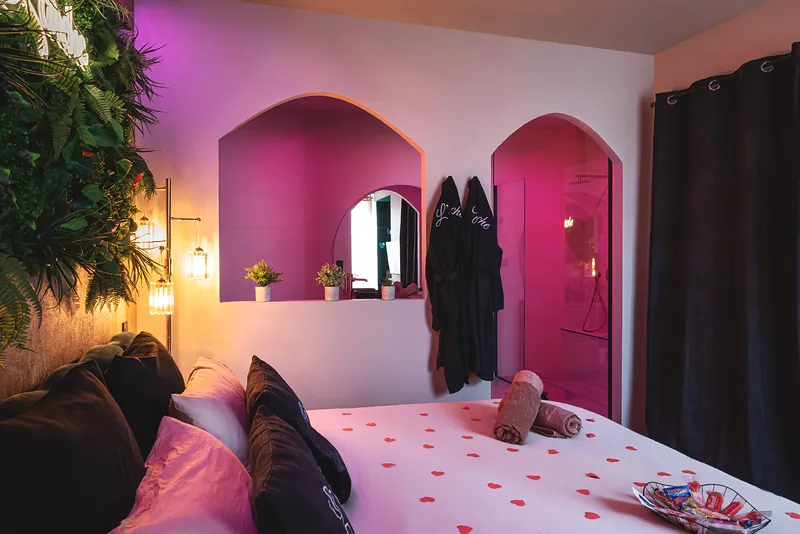 Lit king-size parsemé de pétales, face aux arches rétroéclairées