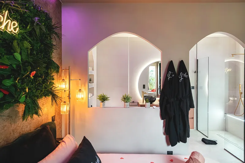 Vue d'ensemble de la suite L'Arche : mur végétal, néon, arches blanches et peignoirs